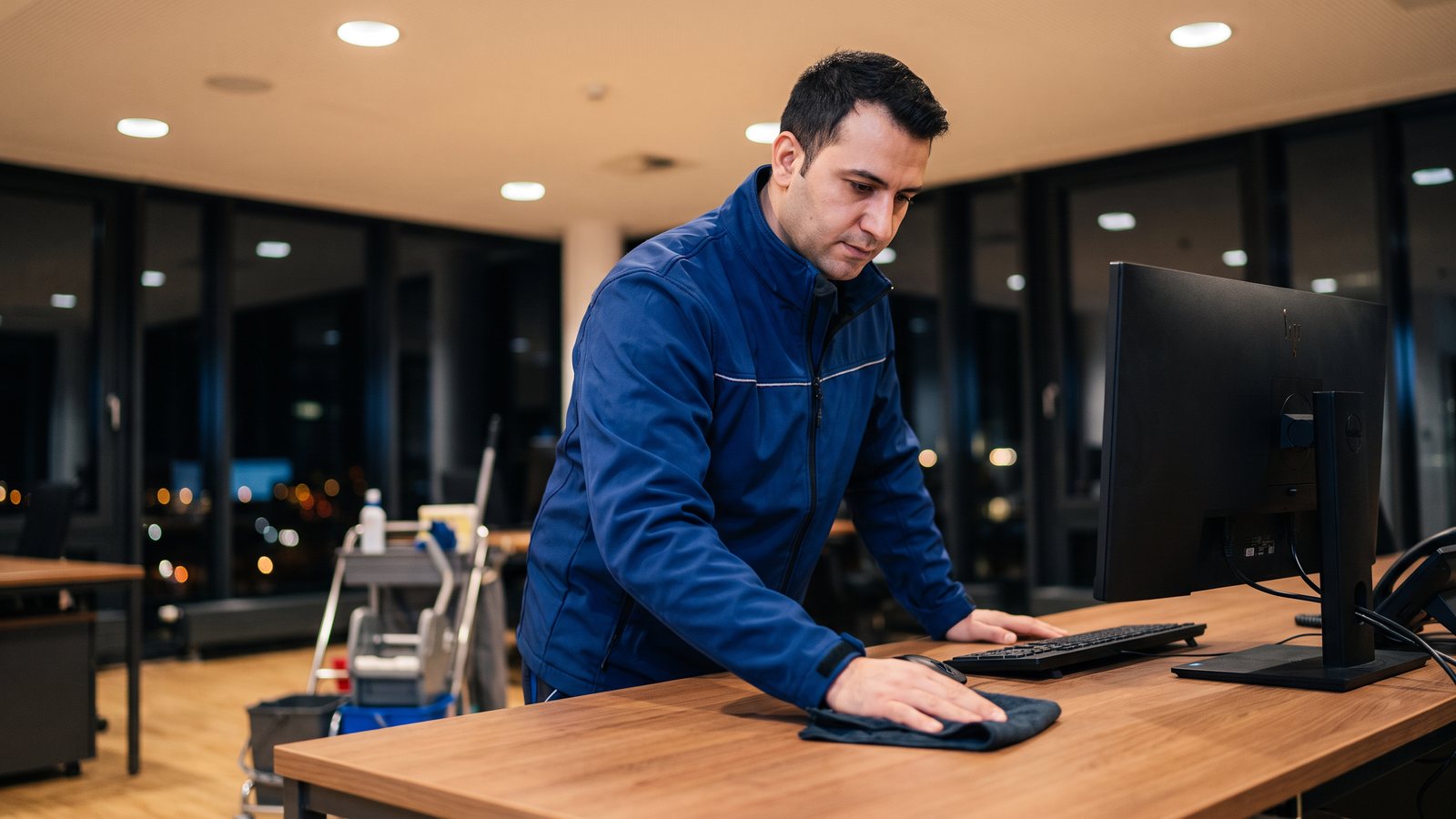 Mitarbeiter von GDE wischt einen Schreibtisch im abendlichen Büro
